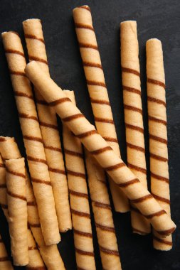 Heap of tasty wafer rolls on black background