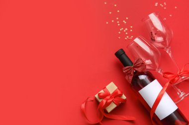 Composition with bottle of wine, glasses and gift for Valentines Day on red background
