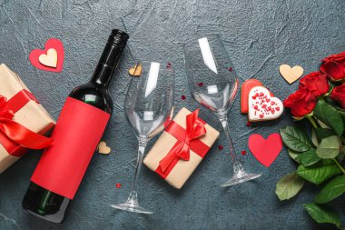 Bottle of wine, rose flowers, gift boxes and hearts on dark table. Valentine's Day celebration