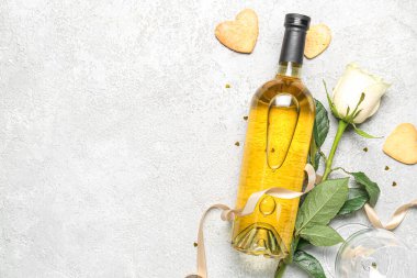 Bottle of wine, rose flower, ribbon and heart-shaped cookies on grey table. Valentine's Day celebration