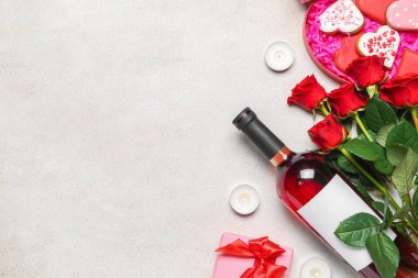 Bottle of wine, rose flowers, gift box and heart-shaped cookies on white table. Valentine's Day celebration
