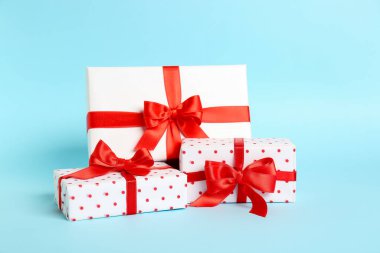 Gift boxes with beautiful bows on blue background. Valentine's Day celebration