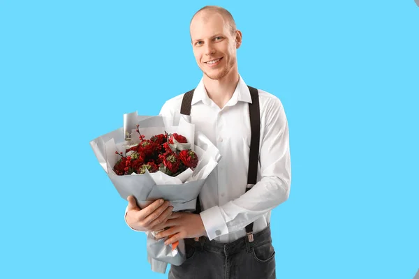 Young man with bouquet of flowers on blue background. Valentine's Day celebration