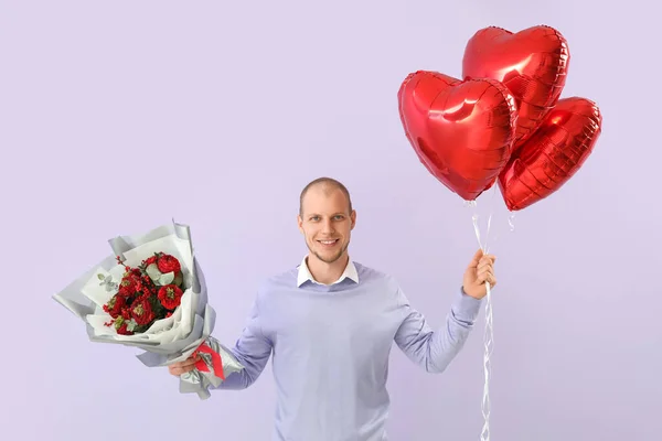 Young man with bouquet of flowers and balloons on lilac background. Valentine\'s Day celebration