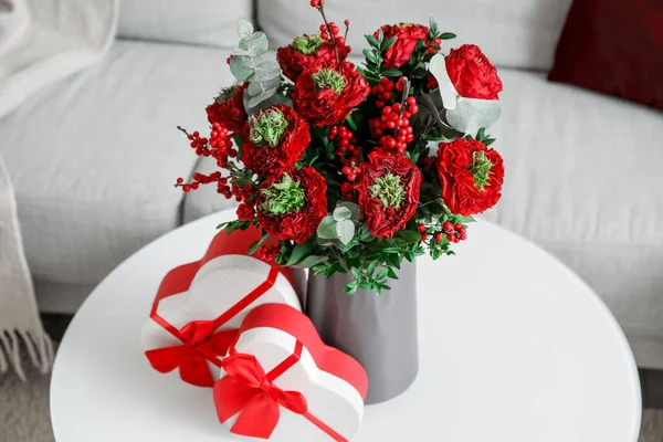 Vase with flowers and gifts for Valentine\'s Day on table in living room, closeup