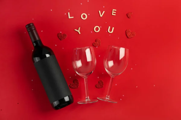 Bottle of wine, words LOVE YOU, glasses and hearts on red background. Valentine\'s Day Celebration