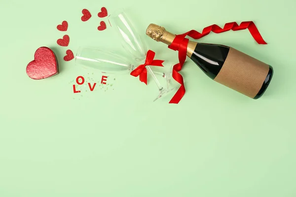 Bottle of wine, word LOVE, glasses and hearts on green background. Valentine\'s Day Celebration