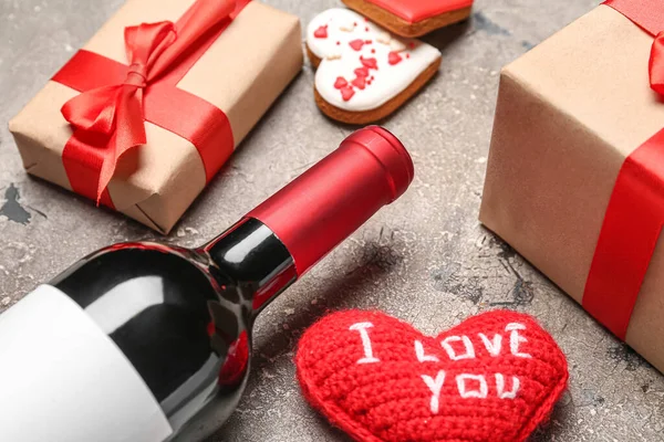 Bottle of wine, heart with text I LOVE YOU and gift boxes on grey table, closeup. Valentine\'s Day celebration
