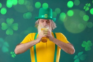 Senior man drinking beer on green background. St. Patrick's Day celebration