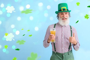 Senior man with glass of beer showing thumb-up on light blue background. St. Patrick's Day celebration
