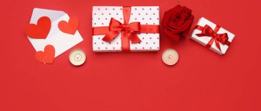 Gift boxes, rose flower, envelope and candles on red background. Valentine's Day celebration