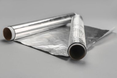 Rolls of aluminium foil on grey background, closeup