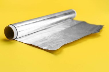 Roll of aluminium foil on yellow background