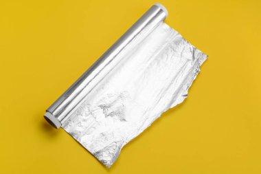 Roll of aluminium foil on yellow background