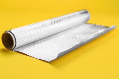 Roll of aluminium foil on yellow background
