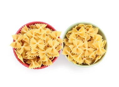 Bowls of raw farfalle pasta on white background