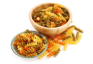 Bowls of raw fusilli pasta isolated on white background