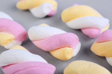 Tasty twisted marshmallows on grey background, closeup