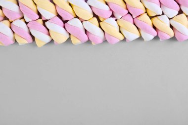 Line made of tasty twisted marshmallows on grey background