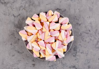 Bowl with delicious twisted marshmallows on grey background