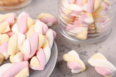 Plate and jar with delicious twisted marshmallows on grey table
