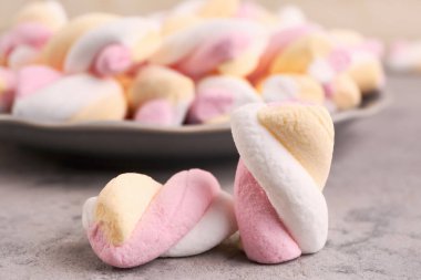 Delicious twisted marshmallows on grey table