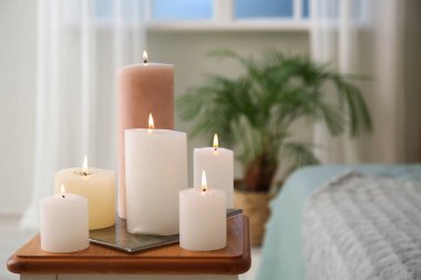 Burning candles on end table in bedroom, closeup