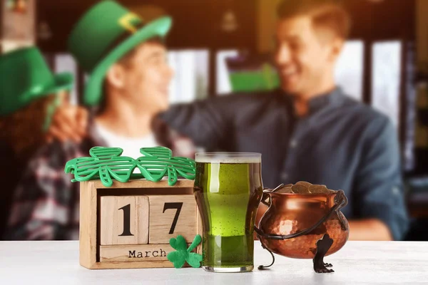 Stock image Calendar with date of St. Patrick's Day, pot with coins and glass of beer on table in bar