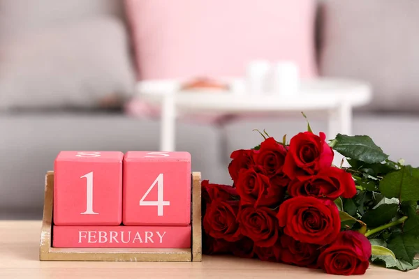 Calendar with date 14 FEBRUARY and roses on table in living room, closeup