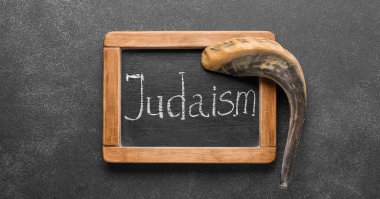 Shofar and chalkboard with word JUDAISM on black background