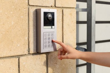 Little girl using intercom on brick wall, closeup