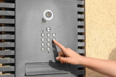 Little girl using modern intercom outdoors, closeup