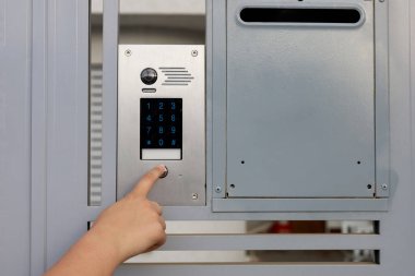 Little girl using modern intercom outdoors, closeup