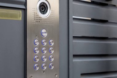 Modern intercom on black fence outdoors, closeup
