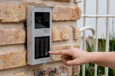 Child using modern intercom on brick wall, closeup