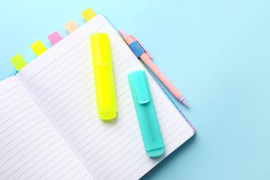 Notebook with sticky notes, markers and pen on color background