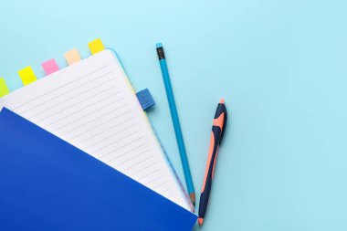 Notebooks with sticky notes, pencil and pen on color background