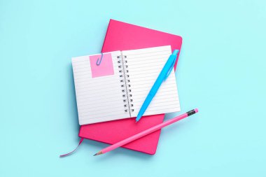 Notebooks, pen and pencil on color background