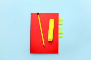 Notebook with sticky notes, marker and pencil on color background