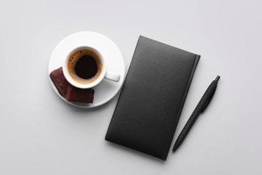 Notebook, pen and cup of coffee on light background