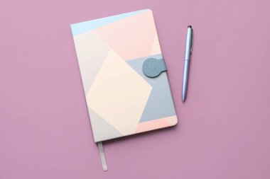 Notebook and pen on lilac background
