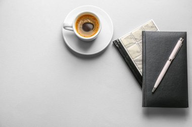 Notebooks, pen and cup of coffee on light background