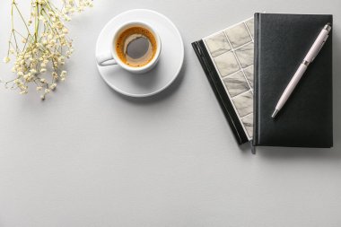 Notebooks, pen and cup of coffee on light background