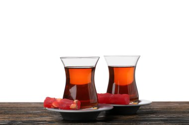 Cups of tasty Turkish tea and sweets on wooden table against white background