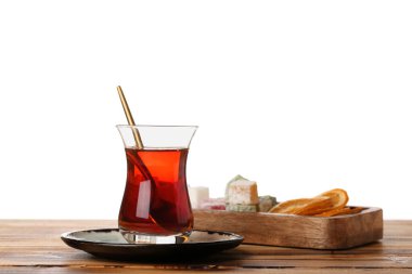 Plate with cup of Turkish tea and sweets on wooden table against white background