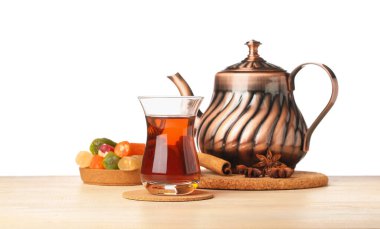 Cup of Turkish tea, teapot, sweets and spices on wooden table against white background