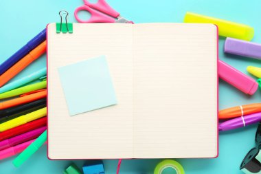 Composition with blank open notebook and different stationery on color background, closeup