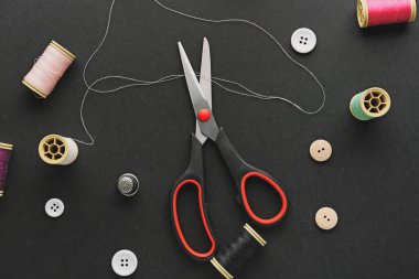 Composition with sewing supplies and scissors on dark background