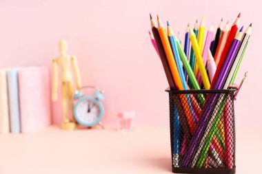 Holder with colorful pencils on pink table, closeup