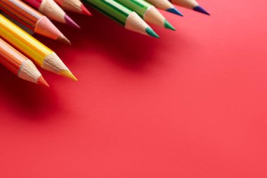 Set of colorful pencils on red background, closeup